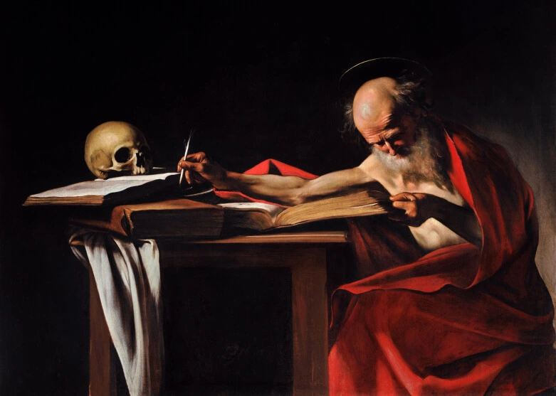 St. Jerome sitting at table in dark room writing in a book, skull, scrolls, and other things adorn the table